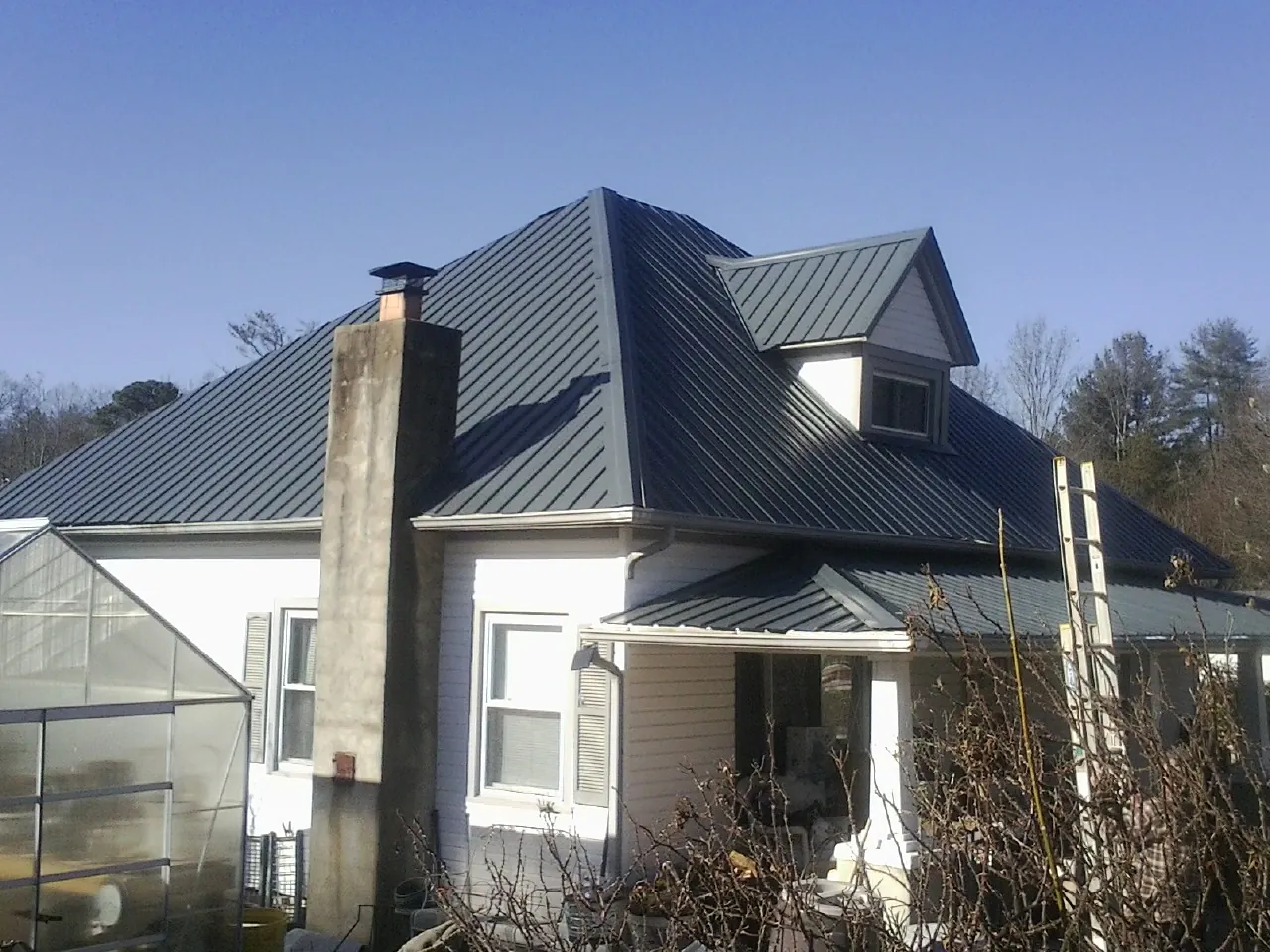 Dark blue standing seam metal roof on a white farmhouse with dormer — Slate & Tile Roof Repair by Roofing Brothers in Mahaffey