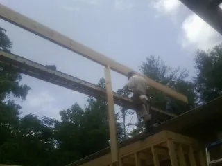 Carpenter setting a ridge beam over a new addition frame — Ice Dam Removal by Roofing Brothers in Mahaffey