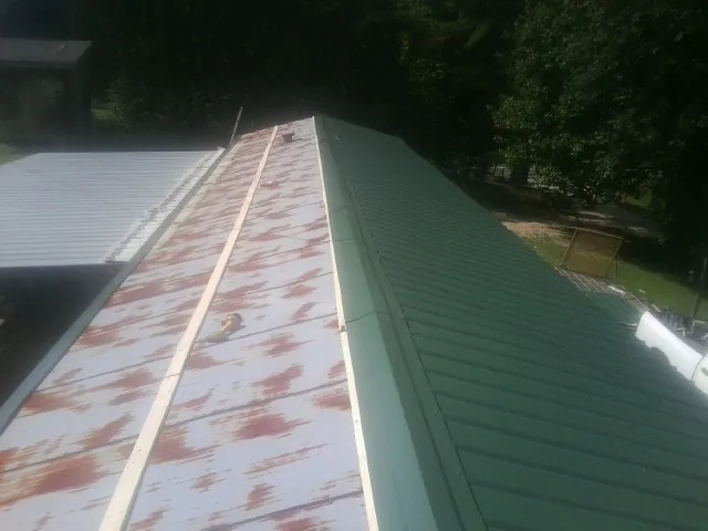 Old rusted panels beside newly installed green metal roofing — Wind Damage Roof Repair by Roofing Brothers in Mahaffey