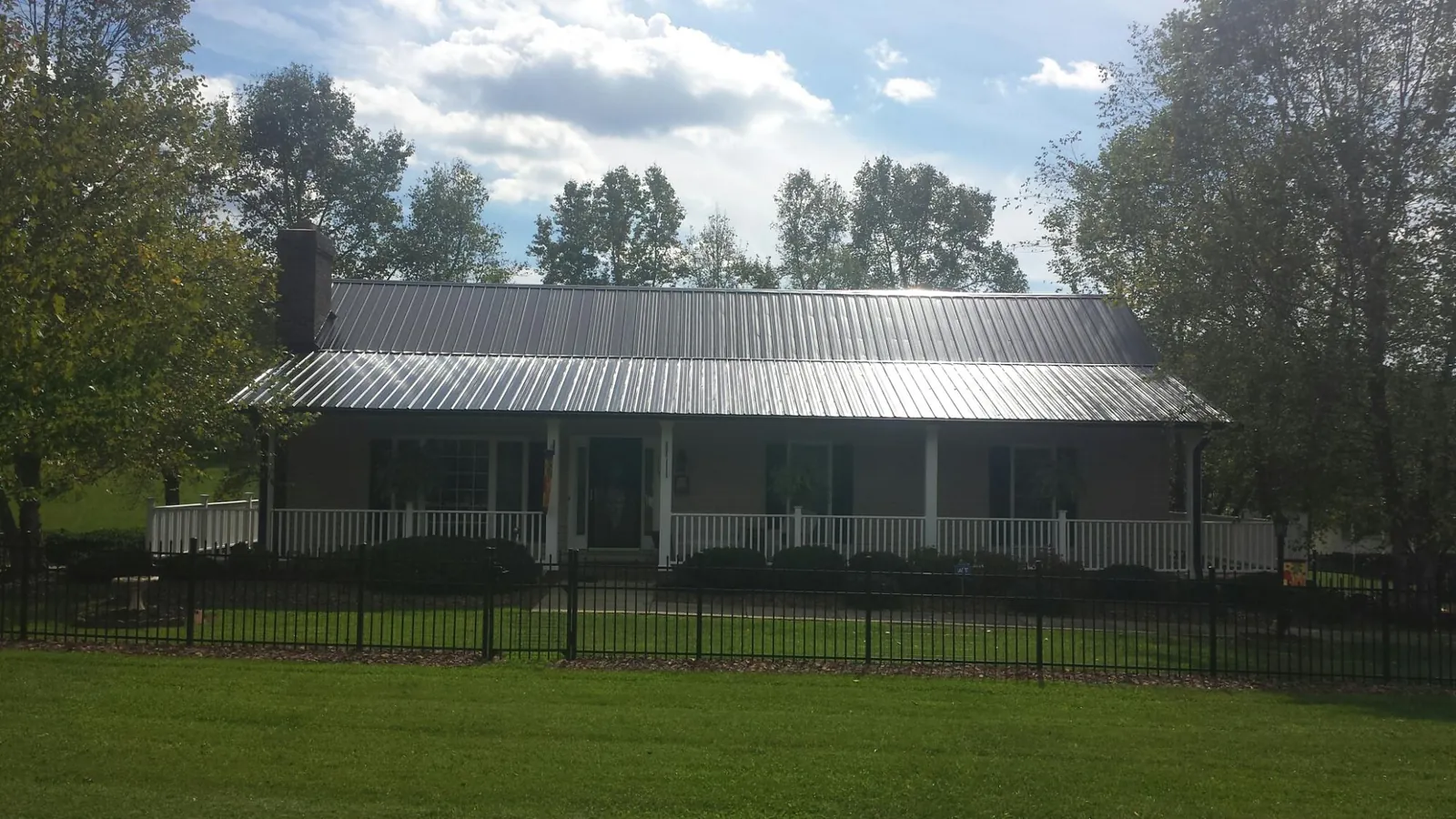 Gray metal roof on a brick ranch with a full width front porch — Gutter Guard Installation work by our crew in Mahaffey