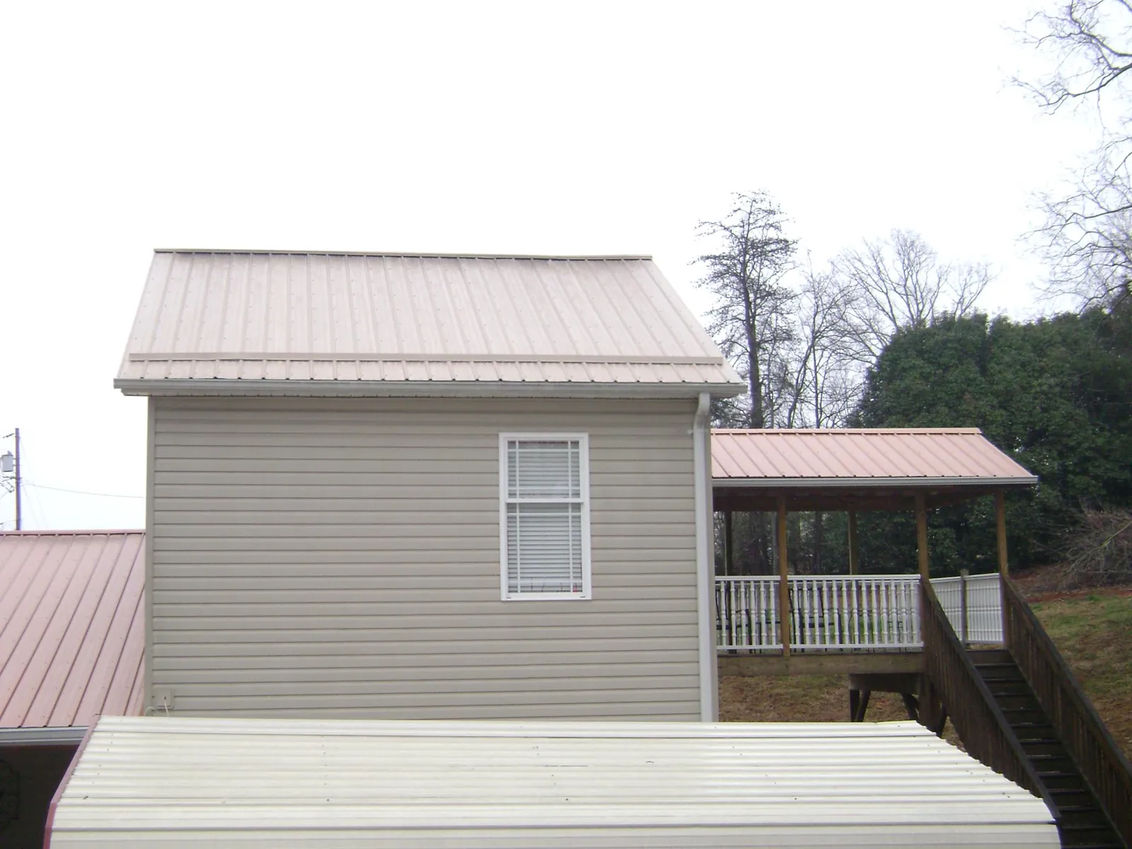Tan metal roofs on a two story addition and attached porch, from a Roof Replacement job in Mahaffey