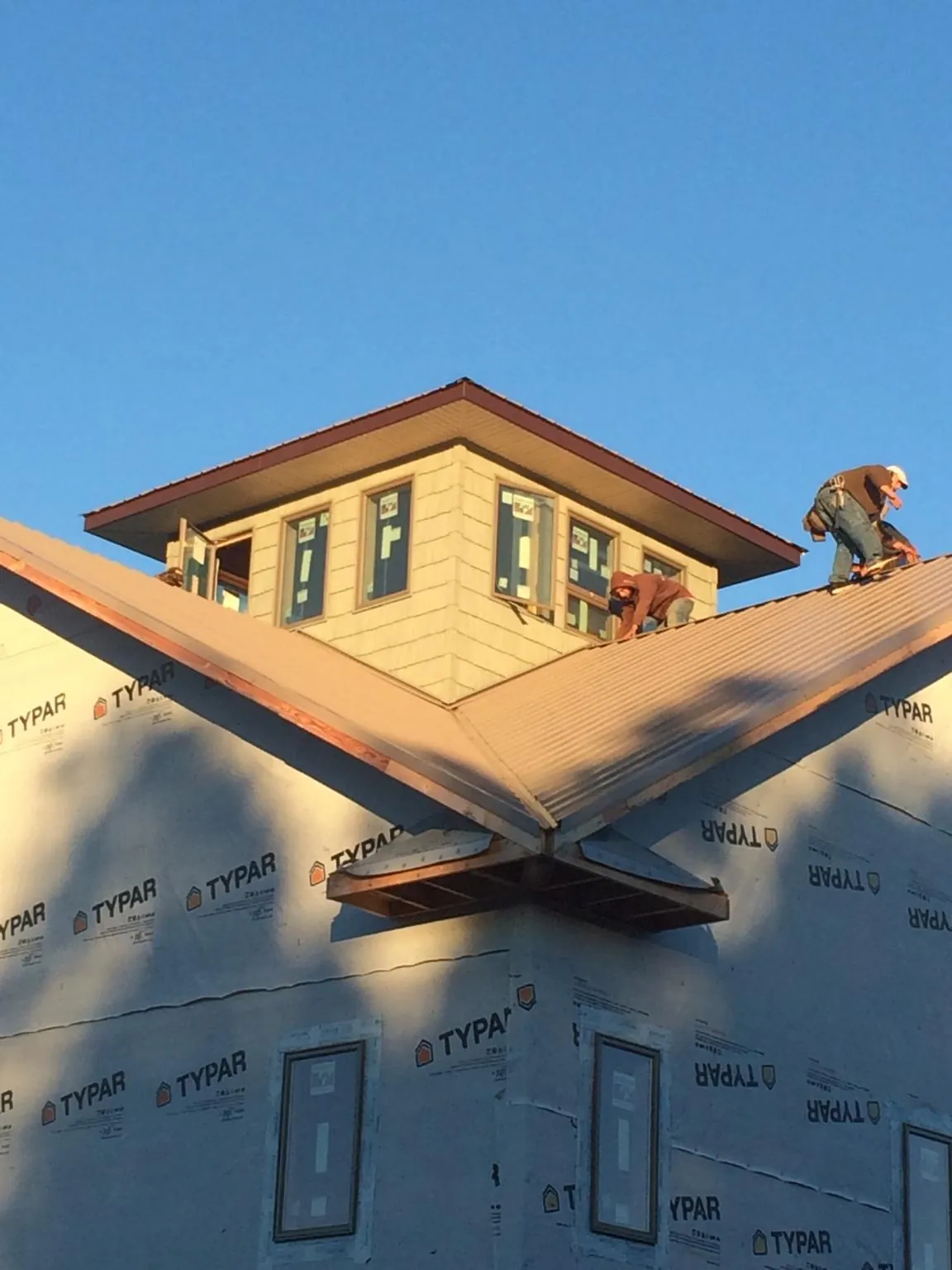 Roofers working around a rooftop cupola on a new metal roof at sunset — Roof Waterproofing in Mahaffey by Roofing Brothers